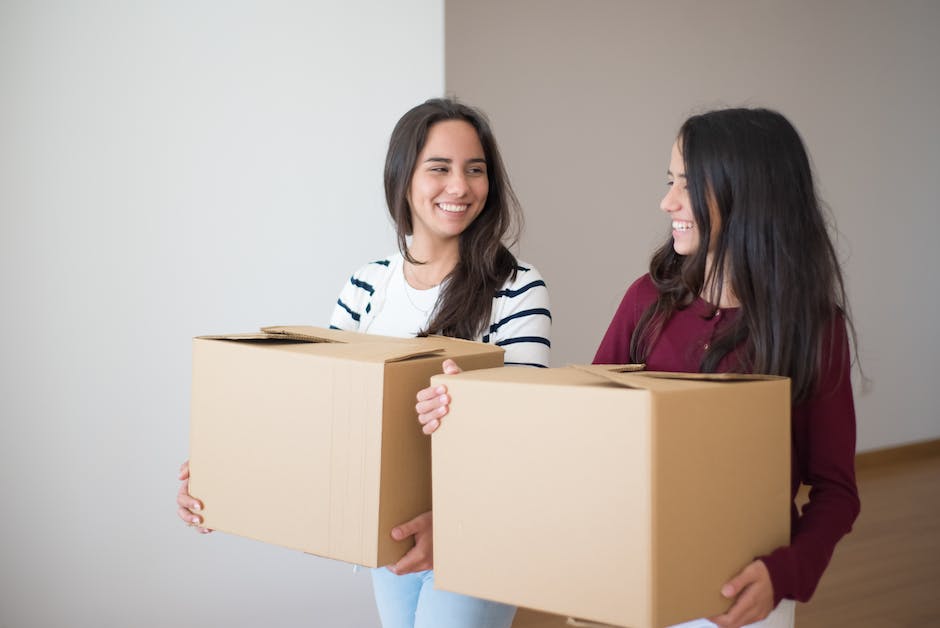 Image description: A person lifting cardboard boxes while moving