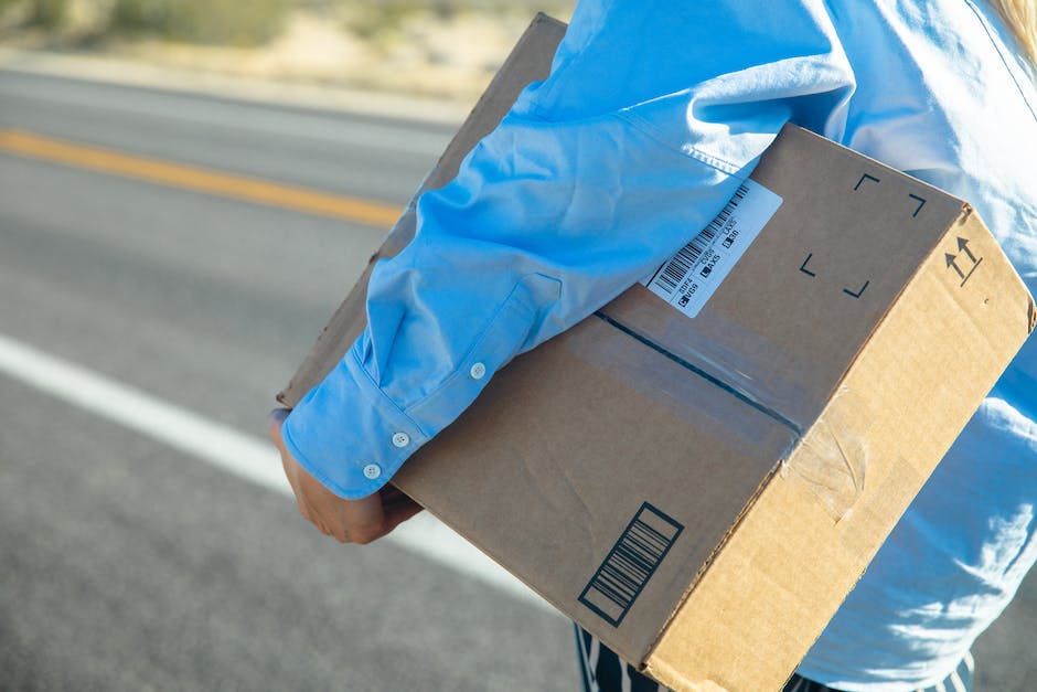 An image of a person carrying a box on their back while walking down a road.